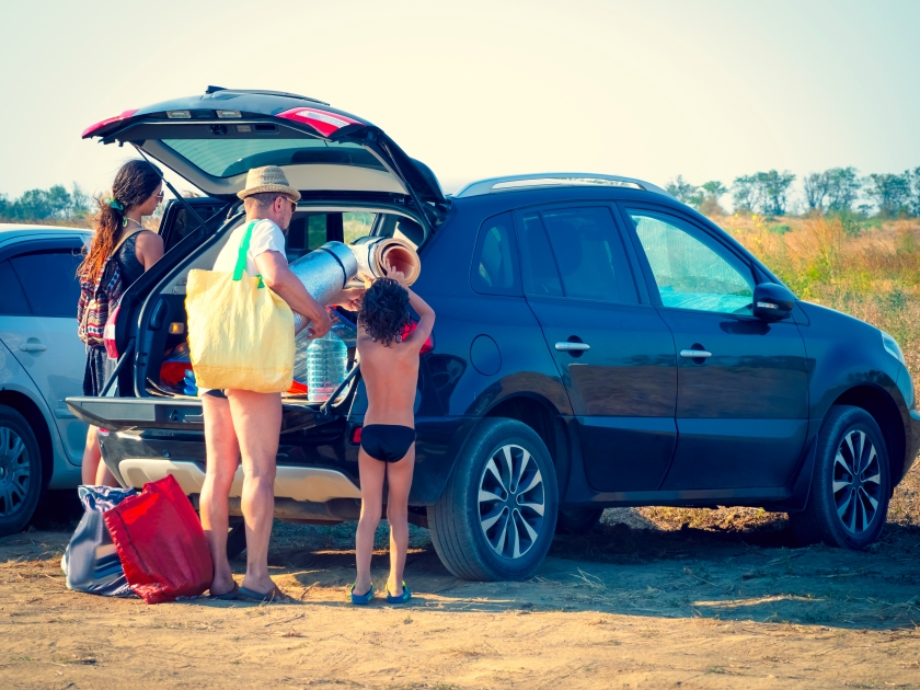 Dad, daughter and grandson stood near the open trunk with suitcases and bags. Family travels by sea, ocean or river. Summer car trip. People who came to the beach by car.