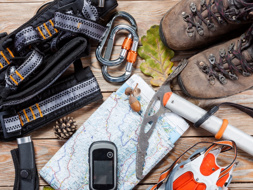 Equipment for mountaineering and hiking on wooden background.