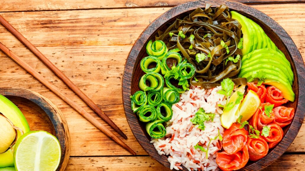 Poke bowl with salmon and vegetables on wooden table