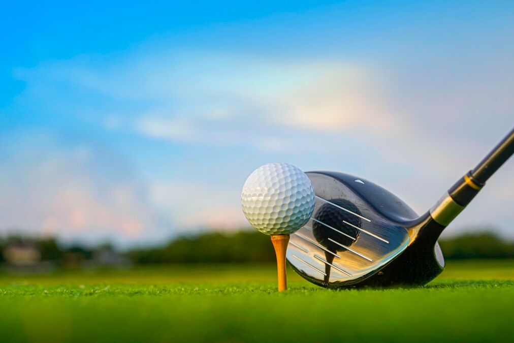 Golf clubs and balls on a green lawn in a beautiful golf course with morning sunshine. Close up of golf equipment on green grass.