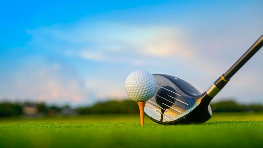 Golf clubs and balls on a green lawn in a beautiful golf course with morning sunshine. Close up of golf equipment on green grass.