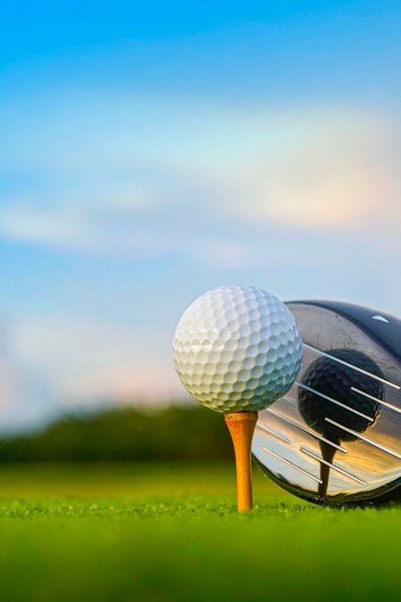 Golf clubs and balls on a green lawn in a beautiful golf course with morning sunshine. Close up of golf equipment on green grass.