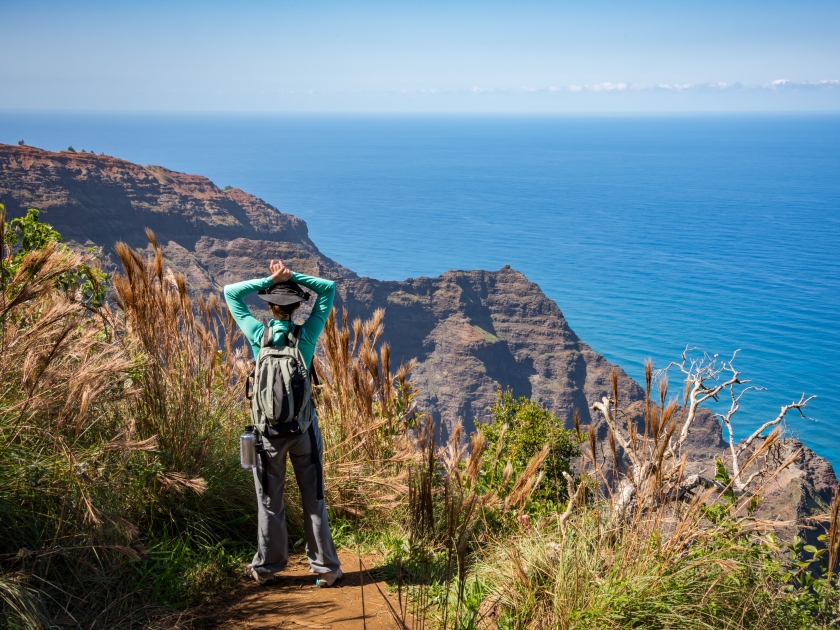 Woman standing at the end of the Awa awapuhi trail on Kauai, Hawaii enjoying the beautiful view of the Na Pali Coast