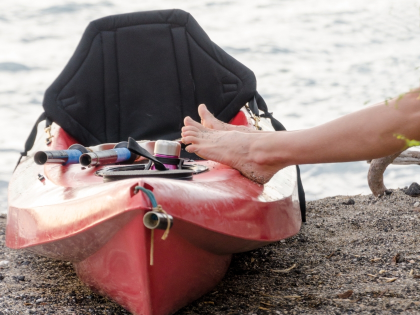 Feet of a woman resting on a canoe at Anaehoomalu beach, Big Island