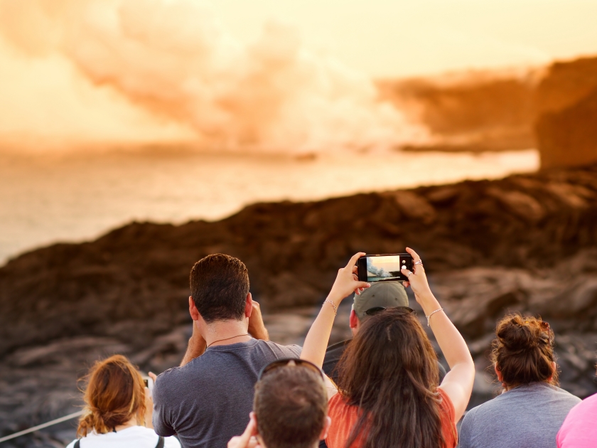 Tourists taking photos at Kalapana lava viewing area. Lava pouring into the ocean creating a huge poisonous plume of smoke at Hawaii's Kilauea Volcano, Volcanoes National Park, Big Island of Hawaii