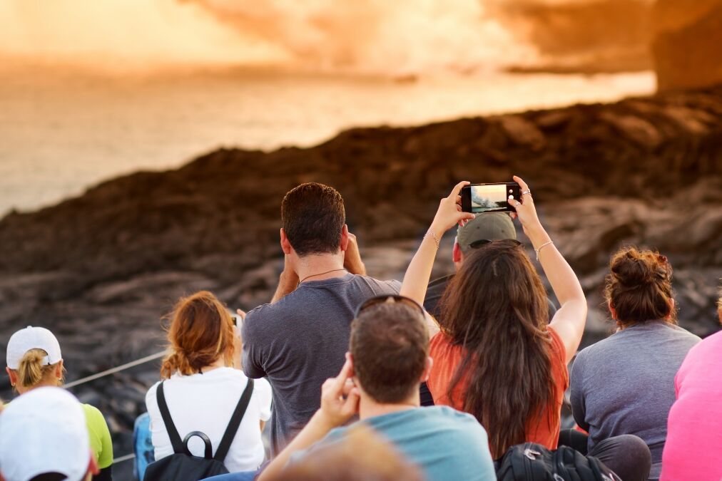 Tourists taking photos at Kalapana lava viewing area. Lava pouring into the ocean creating a huge poisonous plume of smoke at Hawaii's Kilauea Volcano, Volcanoes National Park, Big Island of Hawaii