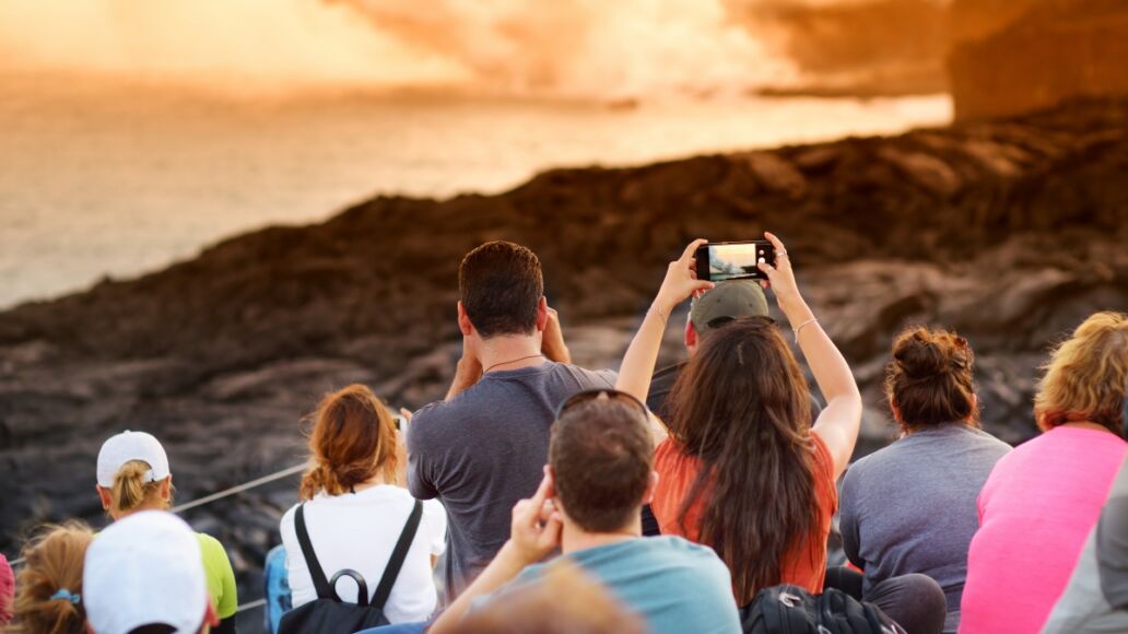 Tourists taking photos at Kalapana lava viewing area. Lava pouring into the ocean creating a huge poisonous plume of smoke at Hawaii's Kilauea Volcano, Volcanoes National Park, Big Island of Hawaii