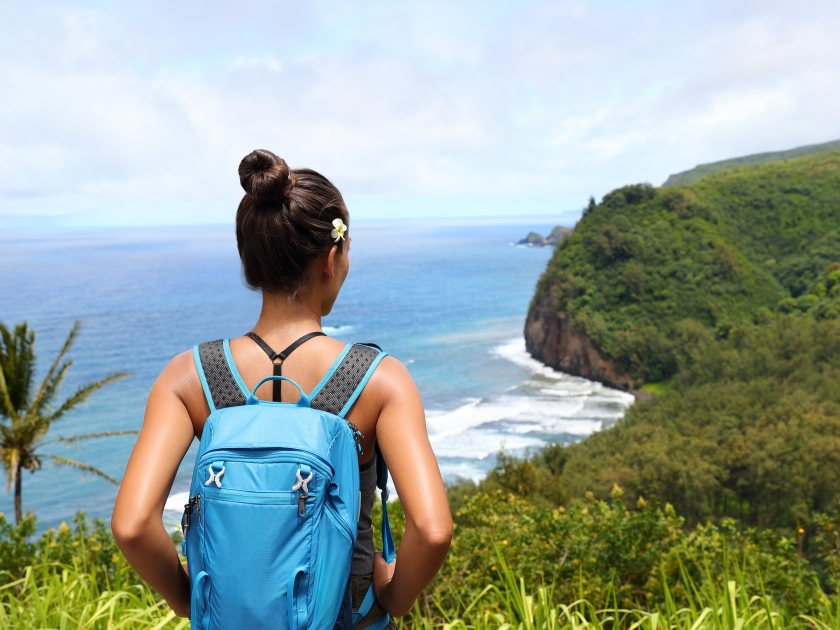Hawaii travel nature hiker girl hiking in Pololu valley enjoying lookout view of mountains. Big island destination, woman tourist in Hawaii, USA.