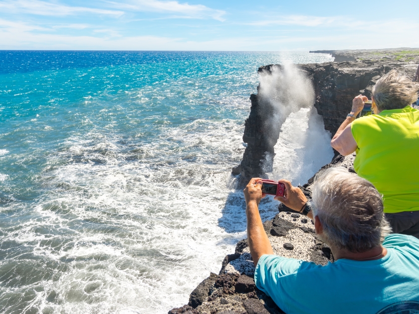 Tourists photographing Holei Sea Arch in Volcanoes National Park, Big Island, Hawaii, Usa