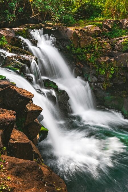 A side view of Hoʻopiʻi Falls, a series of waterfalls along the Kapaʻa Stream, located near Kapaʻa town on the island of Kauai, Hawaii, United States.