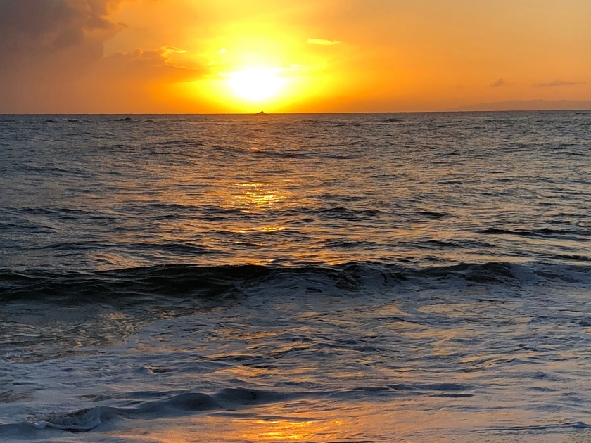 Sunset in Lawai beach, Kaui, Hawai. Yellow sky and sun reflected in the water.