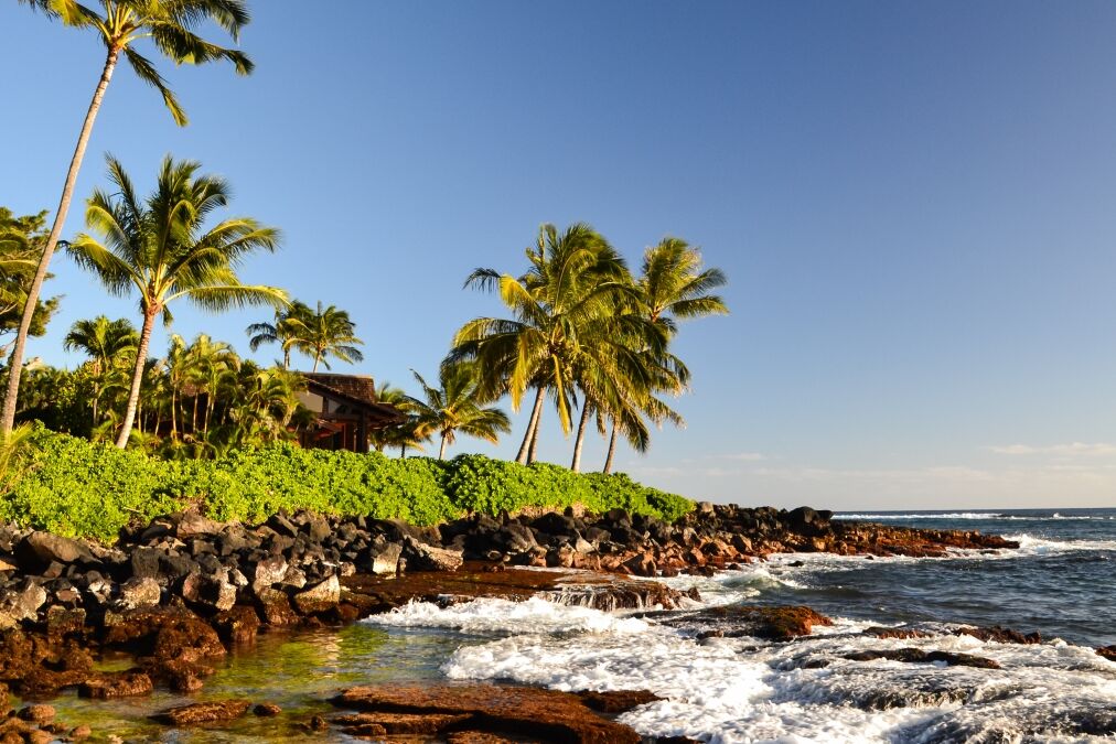 Stunning evening shot of a beach section of Lawai Beach near Poipu on the island of Kauai, Hawaii with palm trees and a beach house at the oceanfront. Poipu is one of the touristic centers of Kauai.