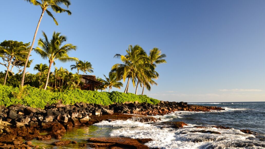 Stunning evening shot of a beach section of Lawai Beach near Poipu on the island of Kauai, Hawaii with palm trees and a beach house at the oceanfront. Poipu is one of the touristic centers of Kauai.