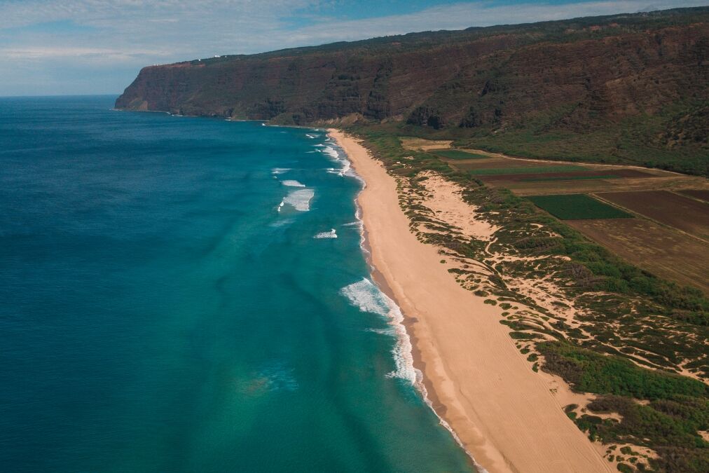 Polihale State park on Kauai drone above showing reef below and waves crashing on the sand