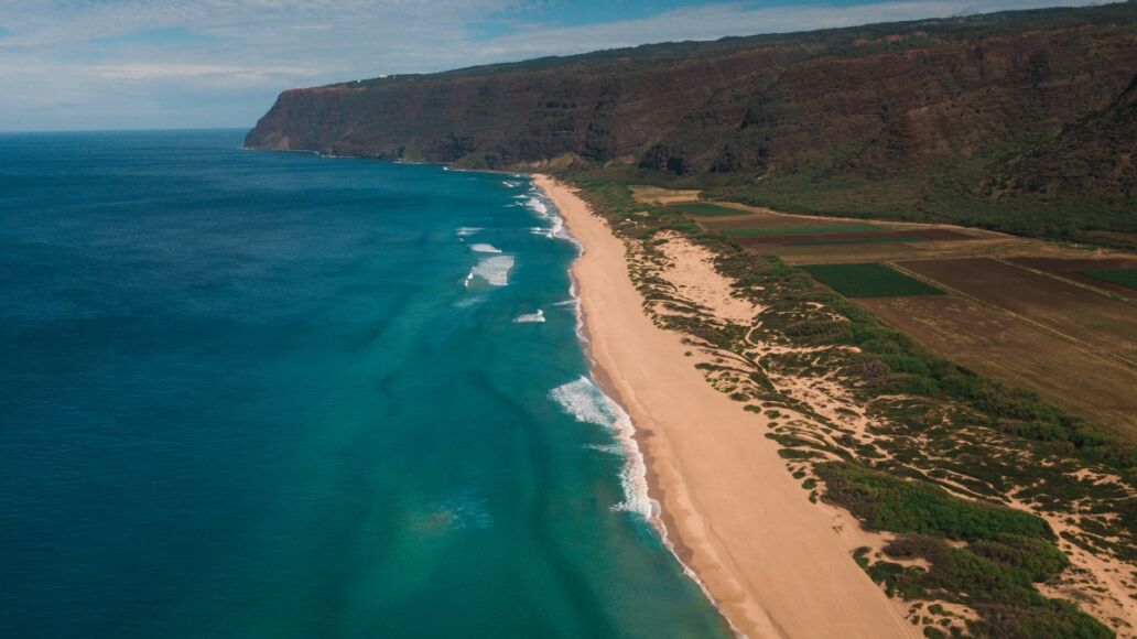 Polihale State park on Kauai drone above showing reef below and waves crashing on the sand