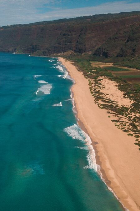 Polihale State park on Kauai drone above showing reef below and waves crashing on the sand