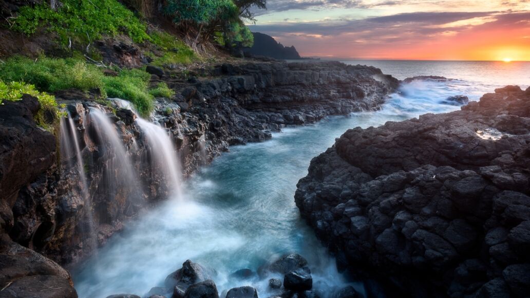 Waterfall near Queen's Bath at sunset, Kauai, Hawaii