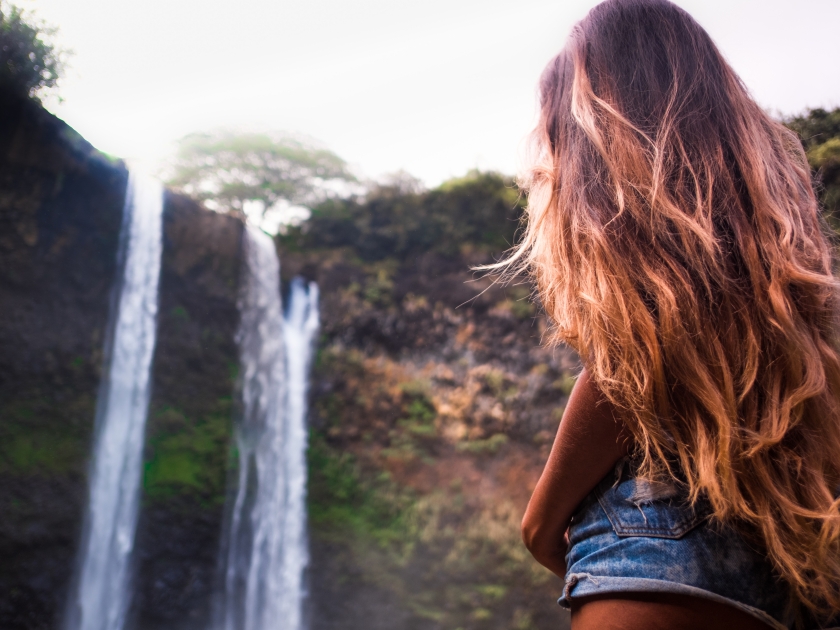 beautiful waterfall in Kauai Hawaii, back of sexy woman with long hair. Woman looks at waterfall . Wailua Falls