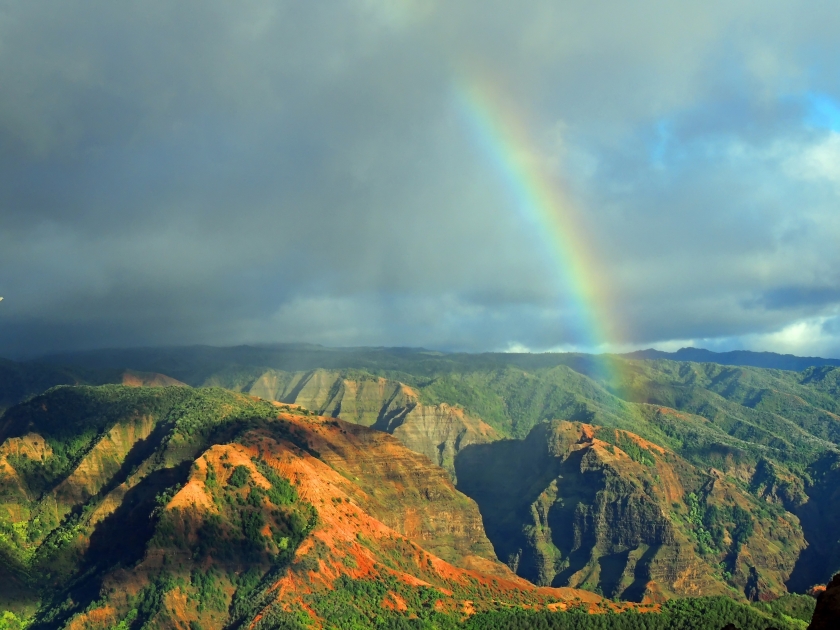 rainbow over colorful waimea canyon on a stormy day in kauai, hawaii