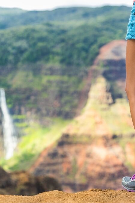 HIking hiker girl at Waimea Canyon Kauai looking at Waipoo falls Hawaii waterfall. Kauai travel.