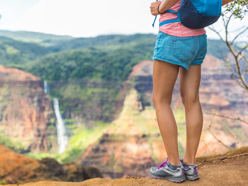 HIking hiker girl at Waimea Canyon Kauai looking at Waipoo falls Hawaii waterfall. Kauai travel.