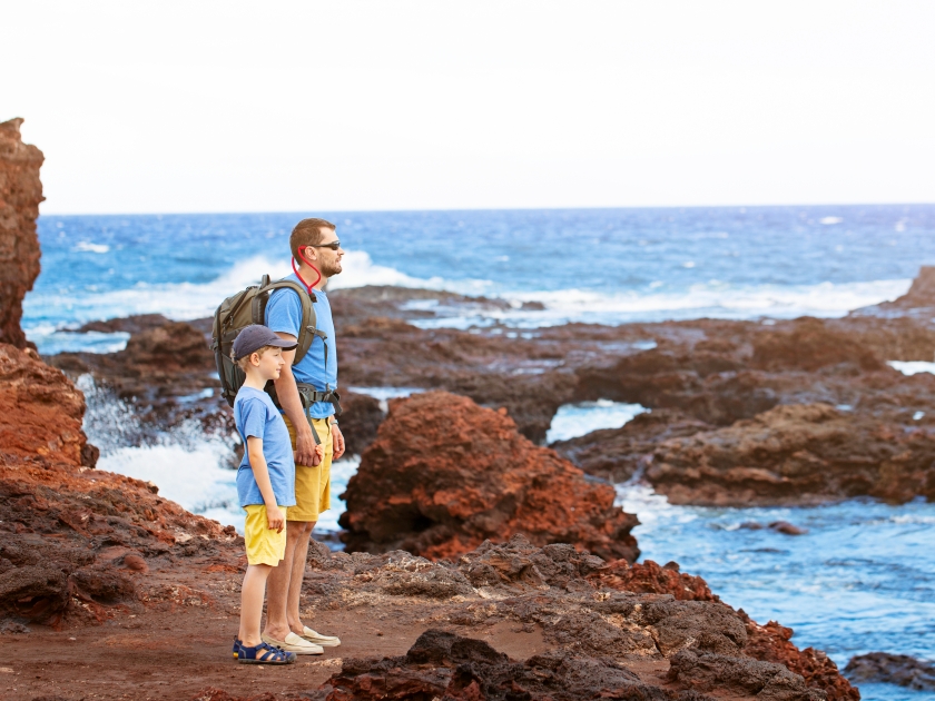 family of two, father and son, enjoying their vacation together at the beautiful rocky hulopoe shore at lanai island, hawaii, family activity concept