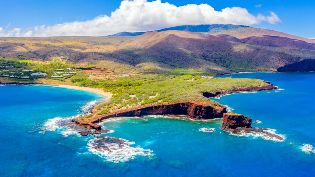 Aerial panoramic view of the island of Lanai, Hawaii, a short ferry ride from Maui, the mountains of which can be seen in the background to the right.