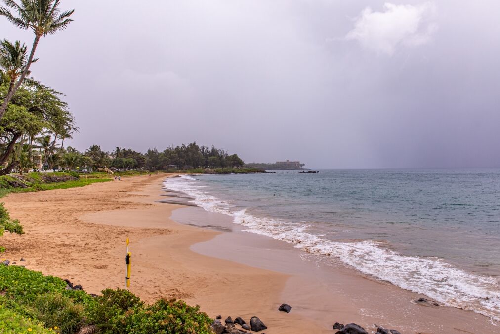 Empty beach of Kamaole Beach III park. People leave the beach in a light of incoming tropical storm Erick warning. Sky is closed with rainy clouds.