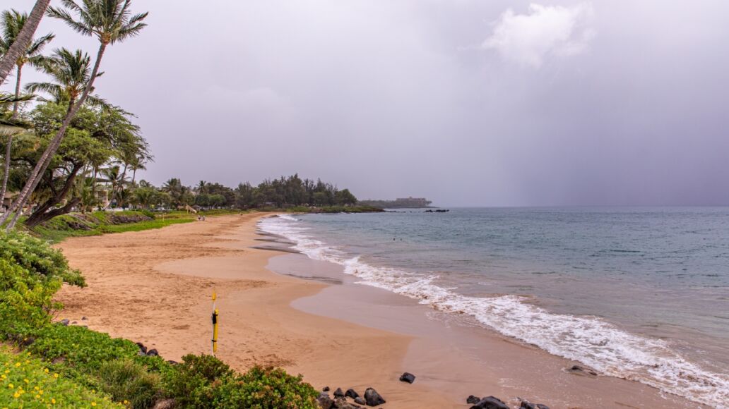 Empty beach of Kamaole Beach III park. People leave the beach in a light of incoming tropical storm Erick warning. Sky is closed with rainy clouds.