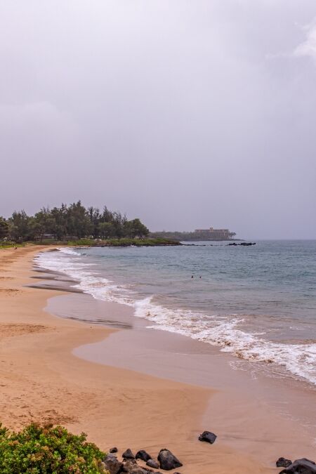 Empty beach of Kamaole Beach III park. People leave the beach in a light of incoming tropical storm Erick warning. Sky is closed with rainy clouds.