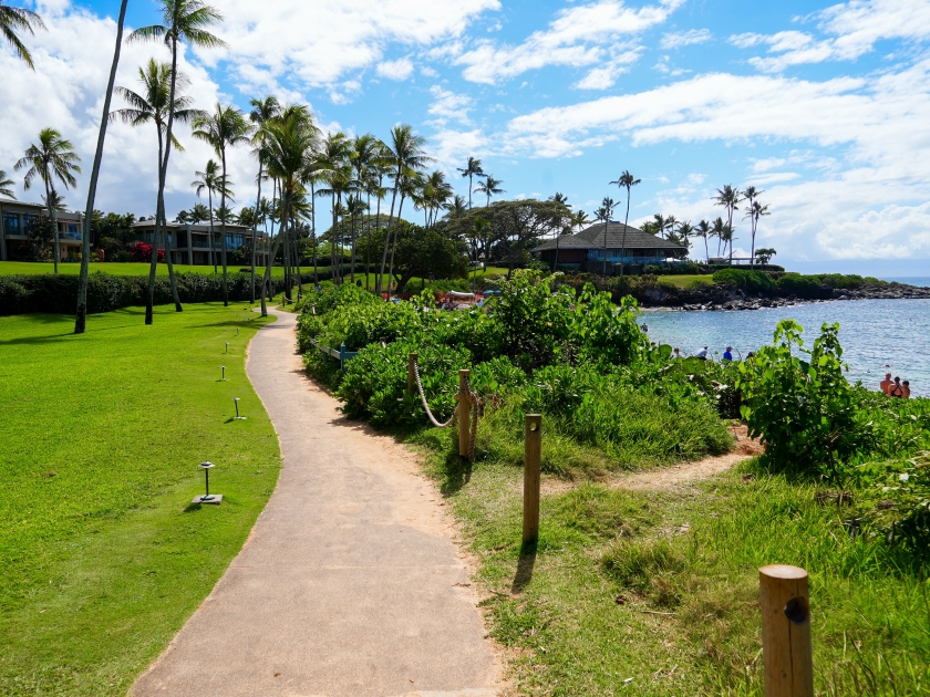 Walking path on the Kapalua Coastal Trail winding between luxury apartment buildings and the beach on Kapalua Bay in West Maui, Hawaii