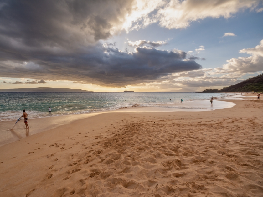 People enjoying Makena Beach during a dramatic sunset in Maui, Hawaii, US.