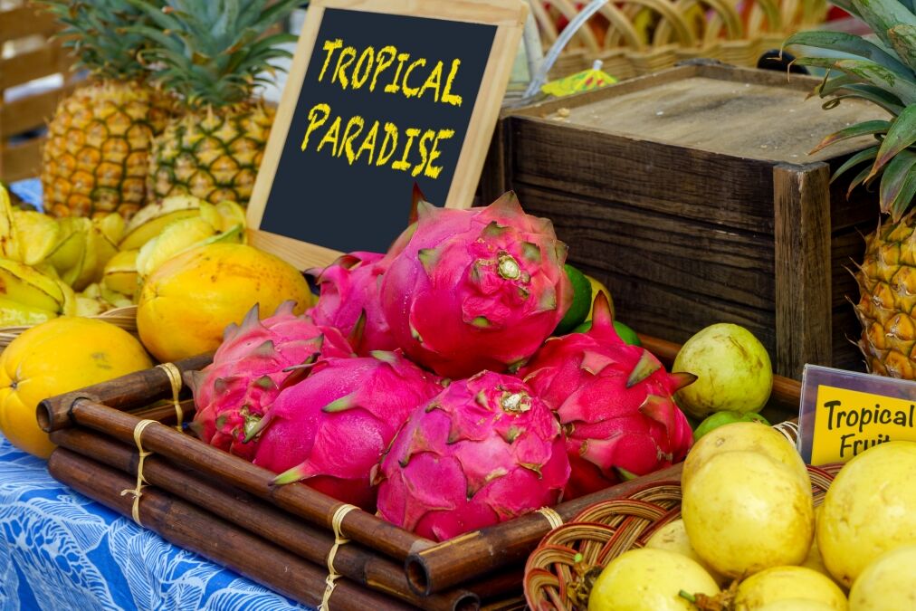 Tropical fruit display of guava, star fruit, pineapple, and dragon fruit at a farmers market