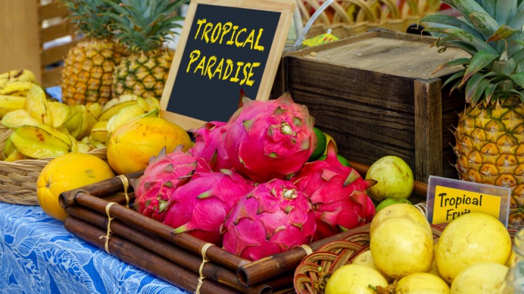 Tropical fruit display of guava, star fruit, pineapple, and dragon fruit at a farmers market