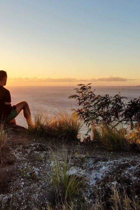 Aerial drone view of three young male hikers enjoying the sunset view on the summit of Diamond Head Crater, a famous tourist destination in Honolulu, Oahu.Hawaii, USA.