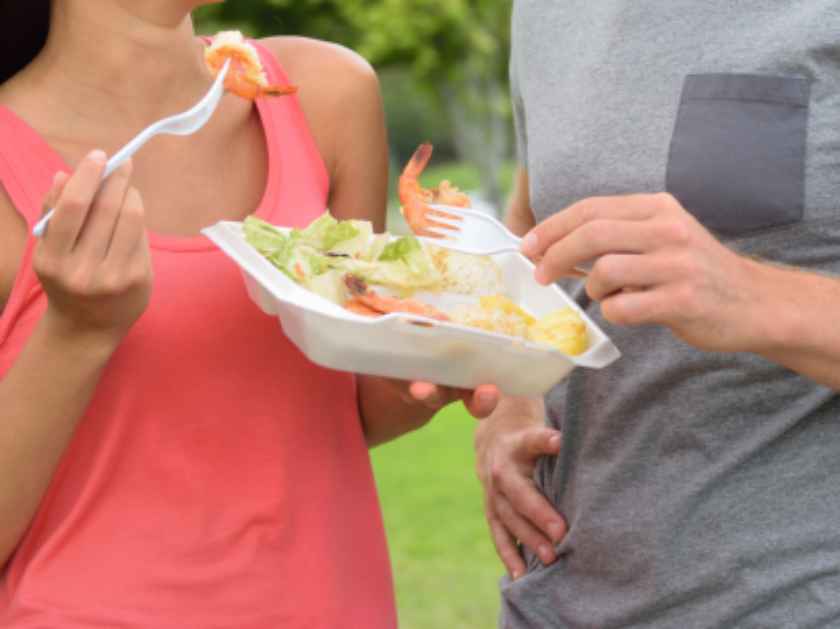 Hawaii food travel couple eating garlic shrimps on Oahu's North Shore. Popular Hawaiian shrimp food truck meal on road trip concept.