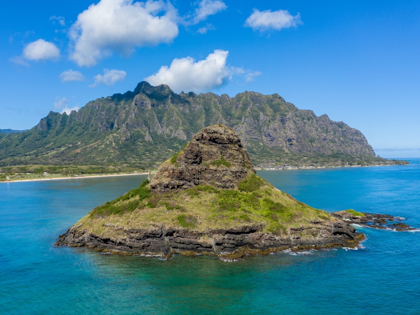Aerial view of the Chinaman's hat with Kualoa beach and park with Ko'olau mountains in the background