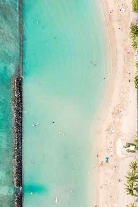 Stunning aerial drone view of Kuhio Beach, part of Waikiki Beach in Honolulu on the island of Oahu, Hawaii. The beach is protected from the ocean through a concrete wall, making it an ocean pool.