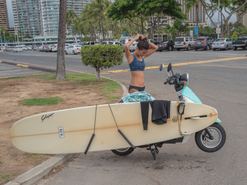 Honolulu, Hawaii, USA, Nov. 28, 2017. Young Hawaiian surfer girl with her surfboard loaded on her scooter for the trip home after a morning of surfing.