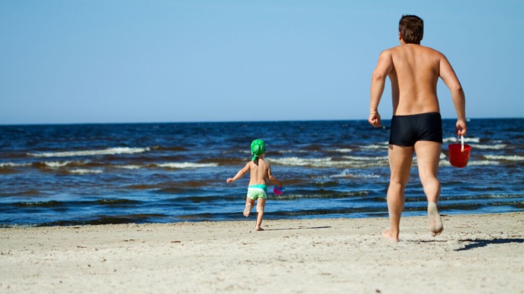 Family of two frolicking on the beach.Some parts in motion (they were running).