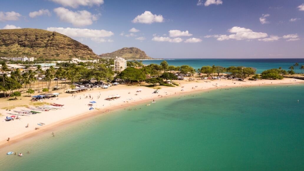 Beautiful aerial image of Pokai Bay beach park and seascape with the clear, blue, tropical waters washing along the shore.