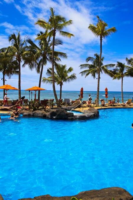 The swimming pool at the Sheraton Waikiki hotel sits at waters edge by the blue Pacific Ocean on Waikiki beach, Hawaii