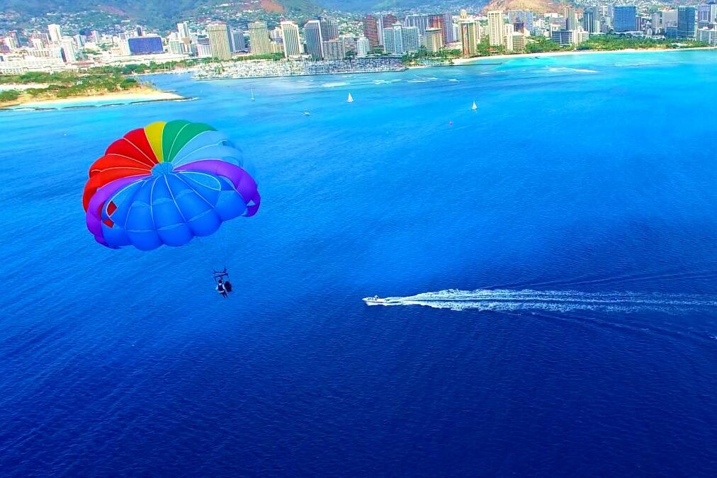 Parasailer With Rainbow Parachute Off The Coast of Honolulu/Waikiki Beach - Aerial Footage in Oahu, Hawaii