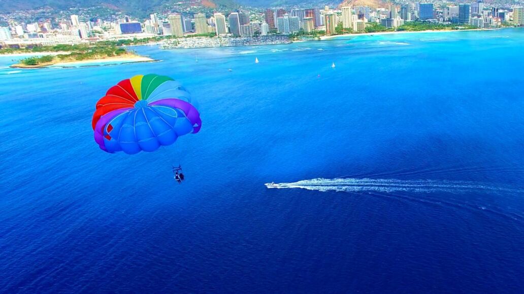 Parasailer With Rainbow Parachute Off The Coast of Honolulu/Waikiki Beach - Aerial Footage in Oahu, Hawaii