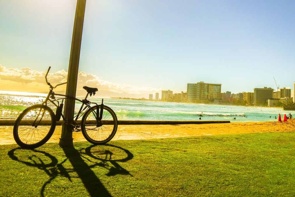 Bicycle on the walkway near the beach with sunset moment and city view in Hawaii silhouette style