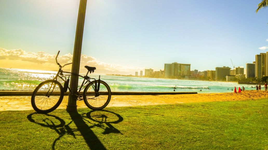 Bicycle on the walkway near the beach with sunset moment and city view in Hawaii silhouette style