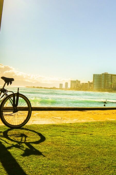 Bicycle on the walkway near the beach with sunset moment and city view in Hawaii silhouette style