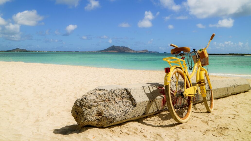 yellow bike leaning next to the concrete pole on the sandy beach