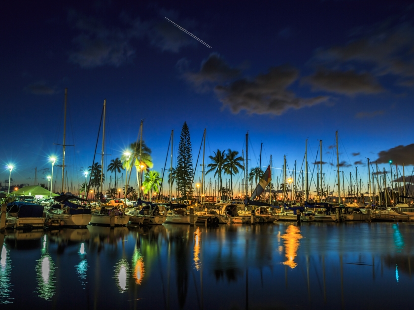 Sailing boats and yachts docked at the Ala Wai Harbor, the largest yacht harbor of Hawaii, reflecting in the sea. Honolulu harbor by night, Oahu, Hawaii.