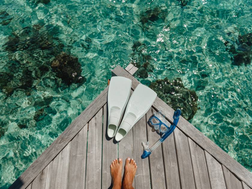 Beach vacation snorkel girl snorkeling with mask and fins. Equipment for snorkeling. Woman legs on wooden pier with snorkeling equipment